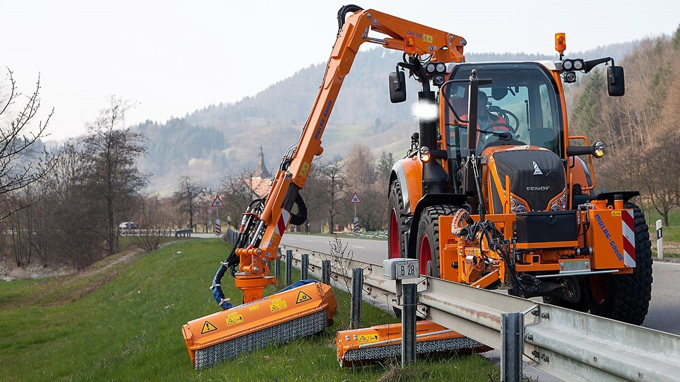 Traktor mit Mähgerät an einem Ausleger.